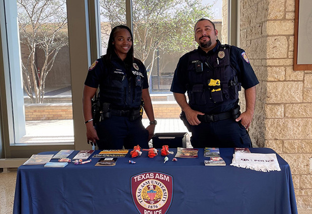 Officers standing at a welcome table at open house